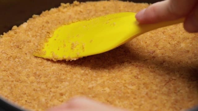 Pressing cheesecake biscuit base with a spatula
