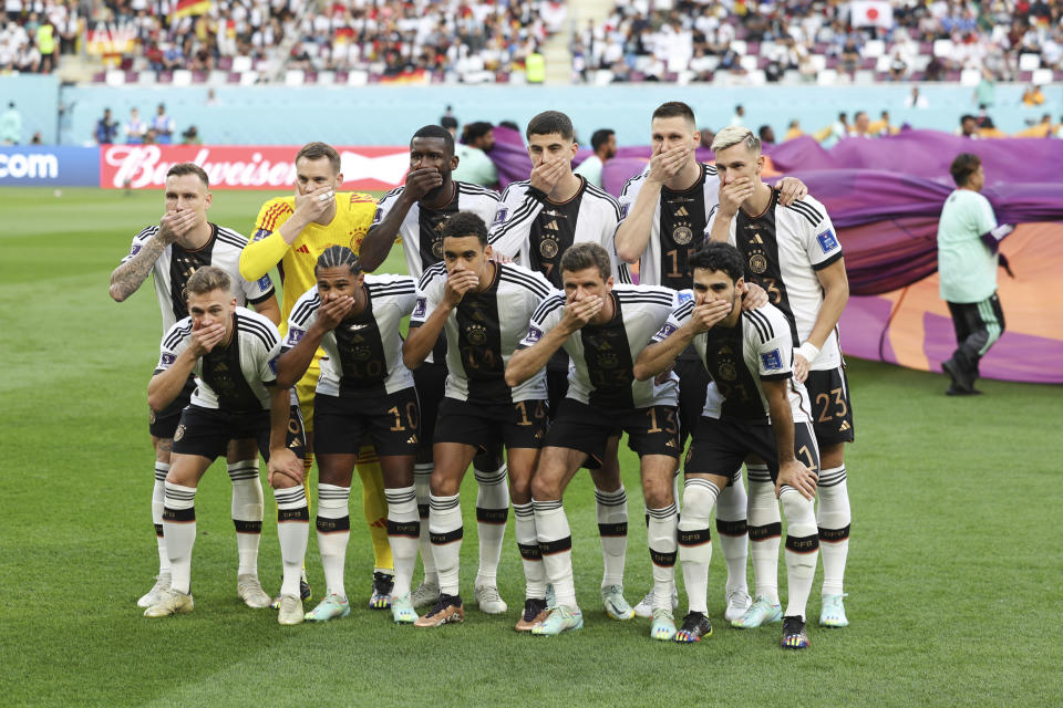 The players of Germany pose with their hands covering their mouths in the team group picture before a match between Germany and Japan at Khalifa International Stadium in Doha, Qatar, on Nov. 23, 2022. (Matthew Ashton - AMA / Getty Images)