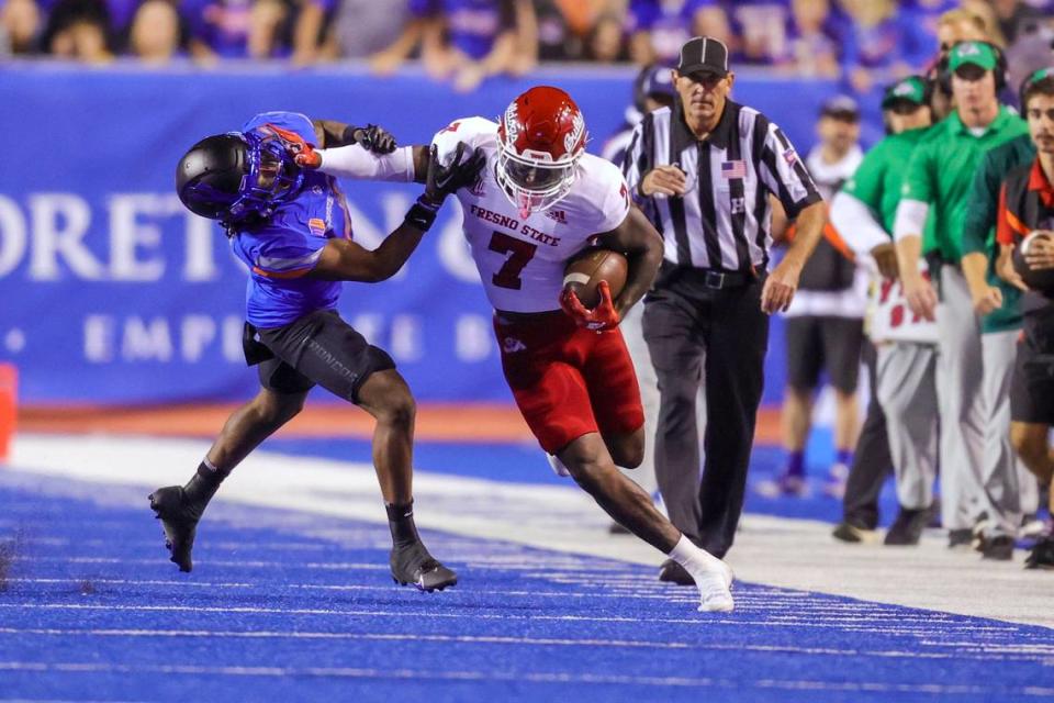 Fresno State running back Jordan Mims (7) stiff-arms Boise State safety Rodney Robinson (4) on a run along the sideline during the first half of an NCAA college football game Saturday, Oct. 8, 2022, in Boise, Idaho. (AP Photo/Steve Conner)