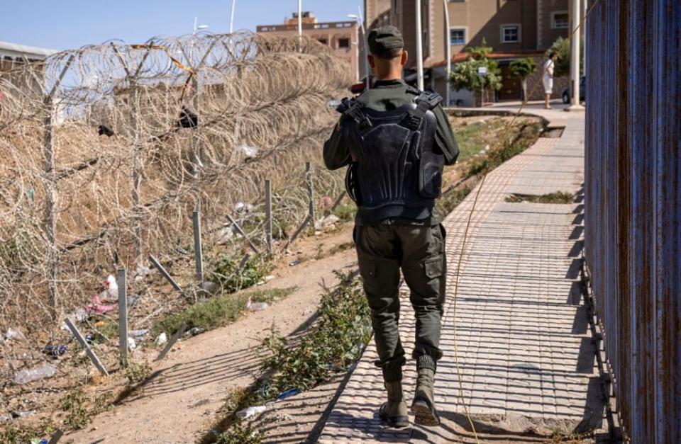 A picture taken on June 26, 2022, shows a member of the Moroccan security forces on the border fence separating Morocco from Spain’s North African Melilla enclave, near Nador in Morocco. – A massive attempt by migrants to storm the barrier between Morocco and the Spanish enclave of Melilla resulted in “unprecedented violence” that killed at least 23 sub-Saharan Africans and has sparked fears of worse to come. (Photo by FADEL SENNA / AFP) (Photo by FADEL SENNA/AFP via Getty Images)