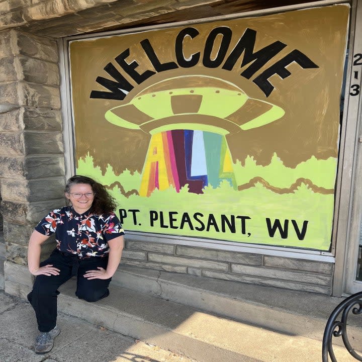 Woman next to a colorful sign with UFO that says 