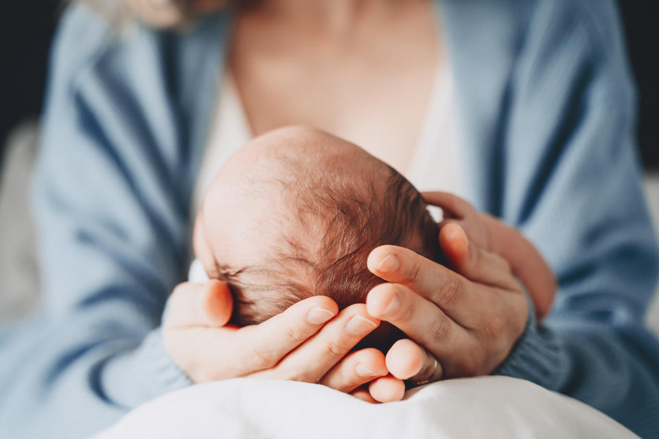 A mother cradling the head of her newborn.