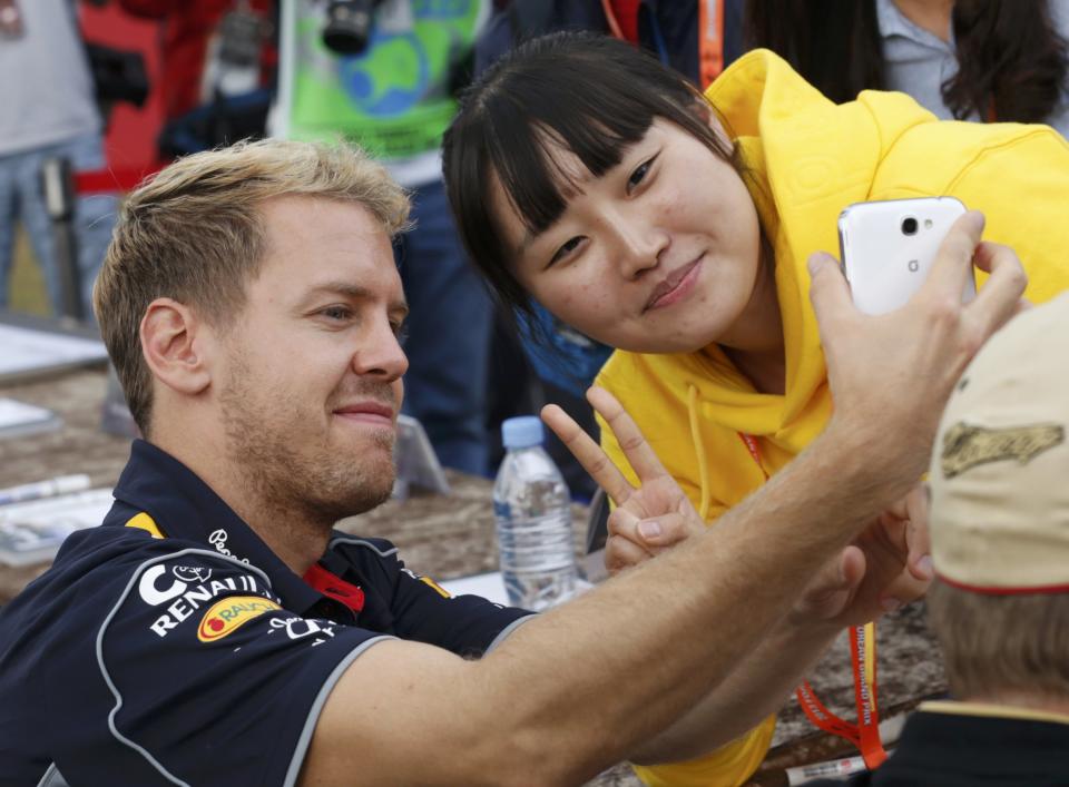 Red Bull Formula One driver Sebastian Vettel of Germany (L) takes a photograph with a fan after the qualifying session for the Korean F1 Grand Prix at the Korea International Circuit in Yeongam, October 5, 2013. REUTERS/Lee Jae-Won (SOUTH KOREA - Tags: SPORT MOTORSPORT F1)