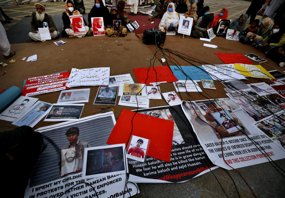 People sit beside the portraits of their missing family members during a sit-in protest, in Islamabad, Pakistan, Saturday, Feb. 20, 2021. Dozens of relatives of Baluch missing persons, allegedly taken away by security agencies from restive Baluchistan province, Saturday ended their ten-day protest sleeping in the February cold near Pakistan parliament in capital Islamabad as minster for Human Rights assured their demand for recovery of loved ones would be taken seriously. (AP Photo/Anjum Naveed)