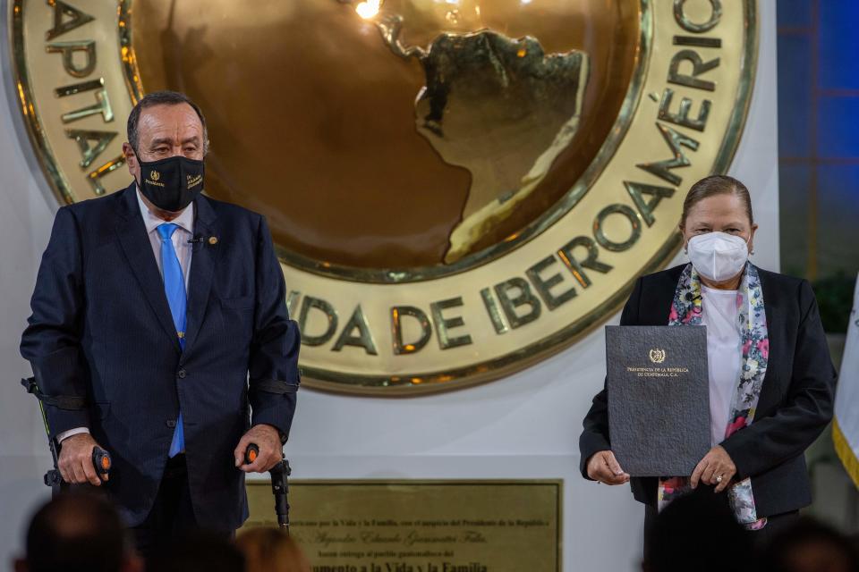 Guatemalan Attorney General Consuelo Porras, left, and President Alejandro Giammattei pose for photos after she was sworn in for another four-year term, at the National Palace in Guatemala City, Monday, May 16, 2022. (AP Photo/Moises Castillo)