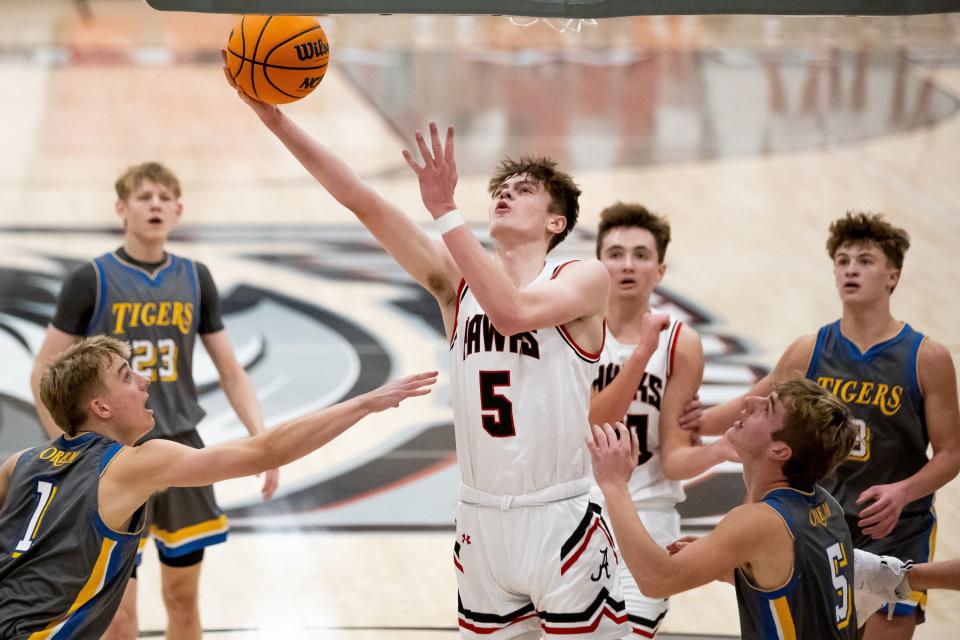 Alta’s Jaxon Johnson drives to the hoop between Orem’s Nick Clark, left, and Lance Reynolds, right, in a high school boys basketball game in Sandy on Tuesday, Jan. 4, 2022. | Spenser Heaps, Deseret News