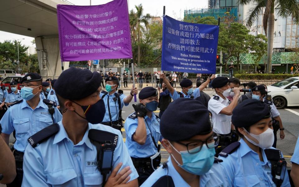 Police officers raise signs warning protesters outside West Kowloon Magistrates' Courts in Hong Kong - LAM YIK /REUTERS 