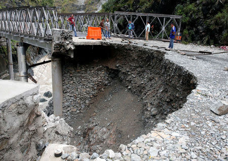 Local residents stand near a road damaged at the height of Typhoon Haima in Benguet province, in northern Philippines, October 21, 2016. REUTERS/Erik De Castro