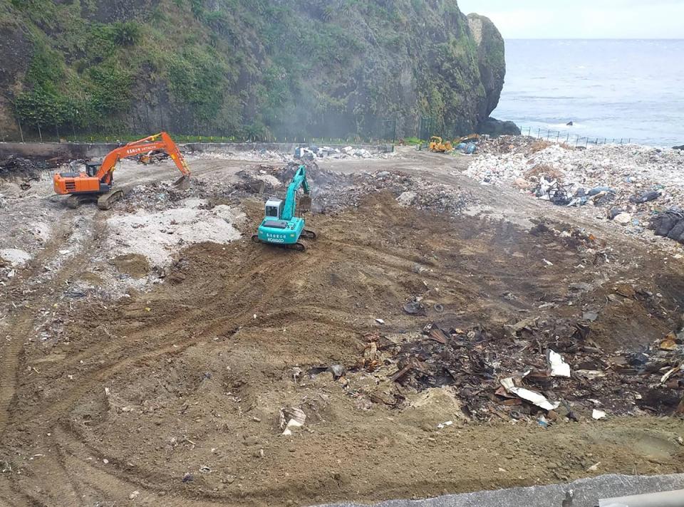 台東縣綠島鄉垃圾場6日凌晨爆炸起火，殘火和濃煙連續竄冒5天，後經鄉公所找來廠商使用怪手挖開垃圾，再灌水滅火，10日上午終於完成燃燒區域土石掩埋，解除危機。（台東縣消防局提供）