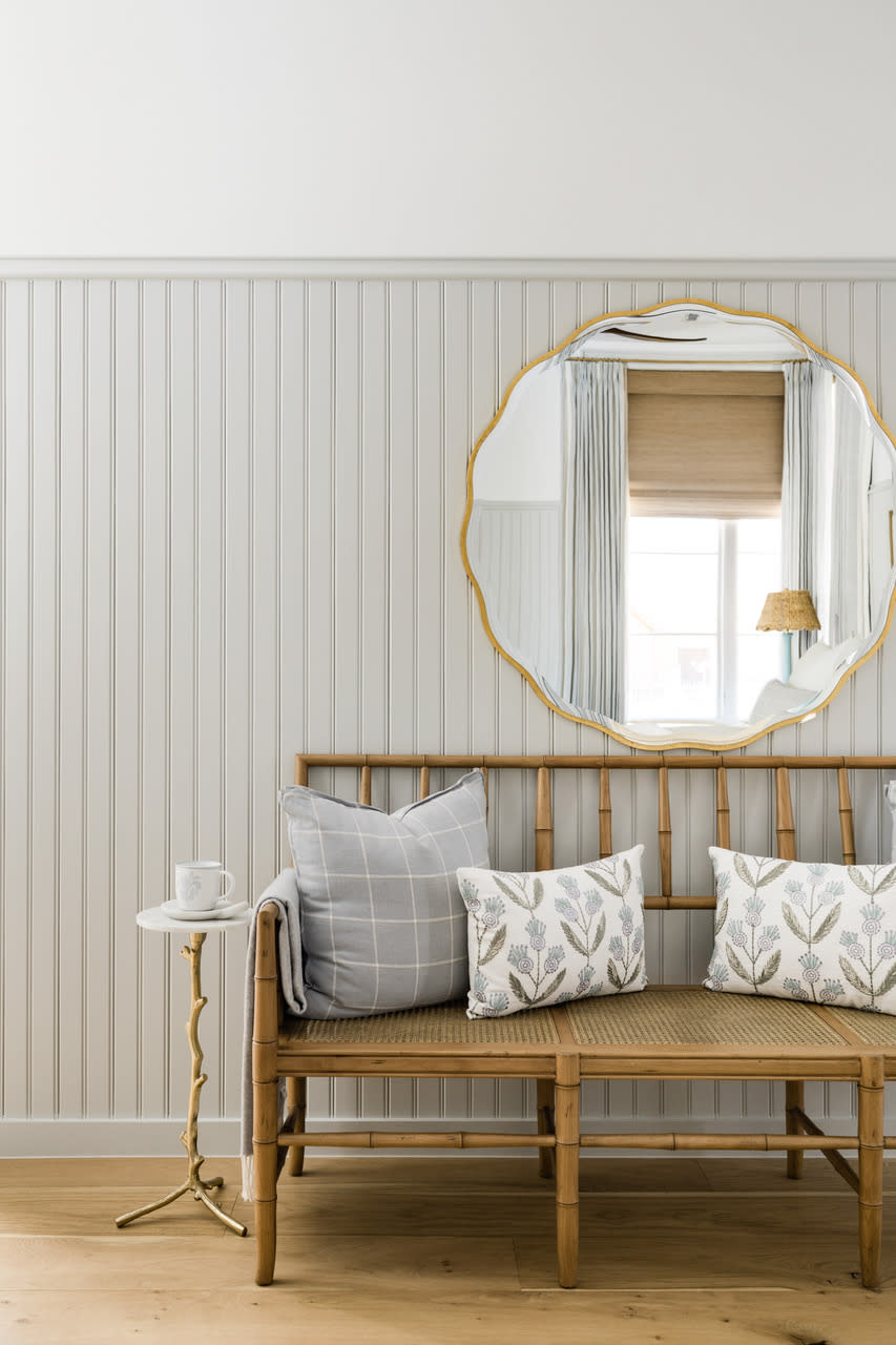 A round mirror above an entryway bench reflecting a window