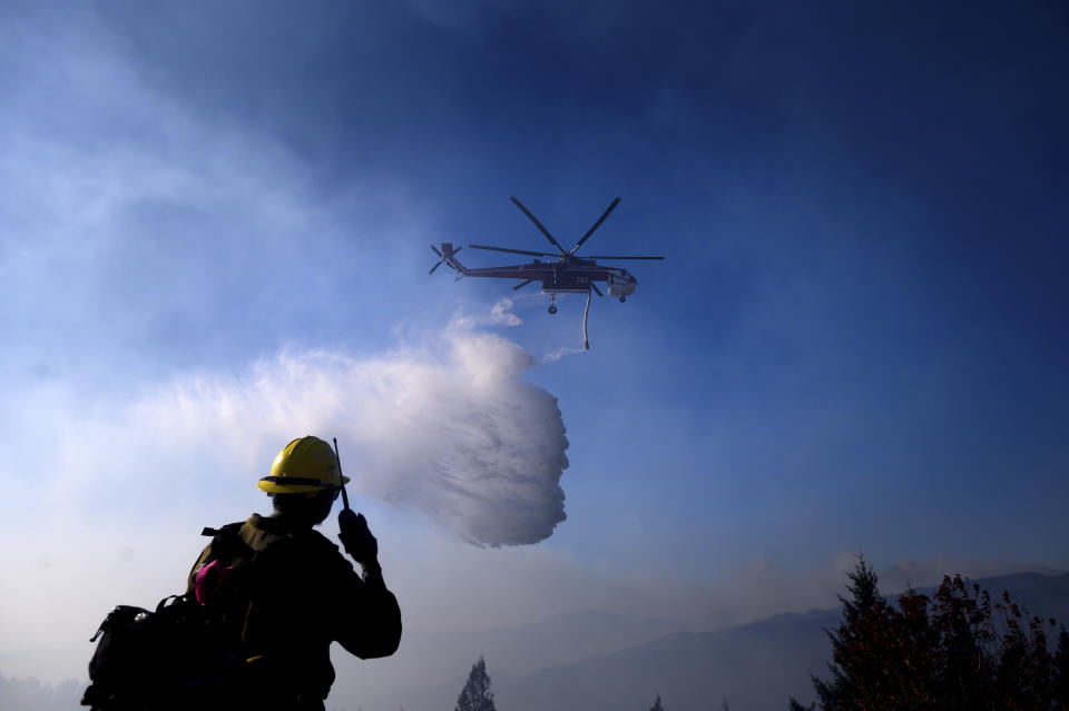 FILE - In this Oct. 29, 2019, file photo a helicopter drops water while battling the Kincade Fire near Healdsburg, Calif. As wildfire risks heat up, startups in California's Silicon Valley are starting to take notice. One startup makes a fire retardant spray that is safe for plants and designed to keep fires from spreading. (AP Photo/Noah Berger, File)