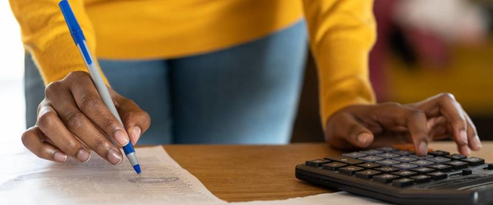 A woman uses a calculator and pen and paper to pay her bills