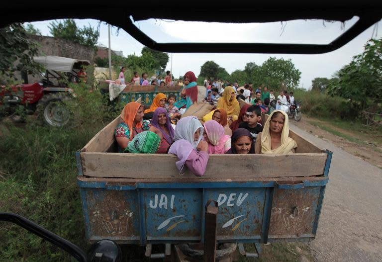 Indian villagers sit in a trailer as they prepare to leave the area following an alleged cross-border exchange between Indian and Pakistani soldiers at Chilayari village in Samba district, Jammu on October 8, 2014