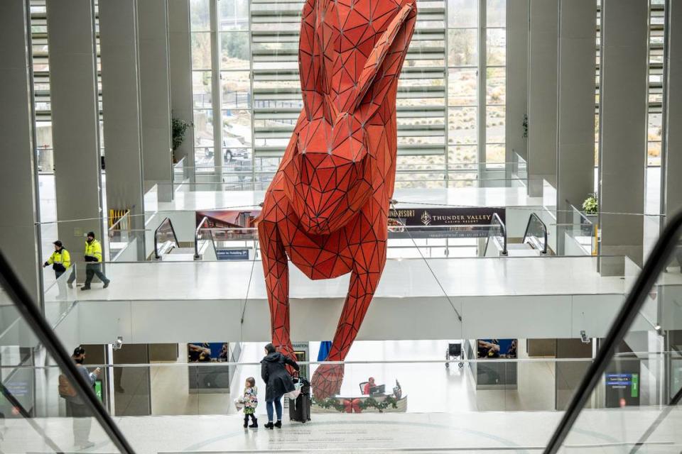 Amy Azzi of Seattle and her daughter look at “Leap” the 56-foot-long red rabbit created by Denver artist Lawrence Argent at the Sacramento International Airport’s Terminal B on Thursday, Dec. 29, 2022.