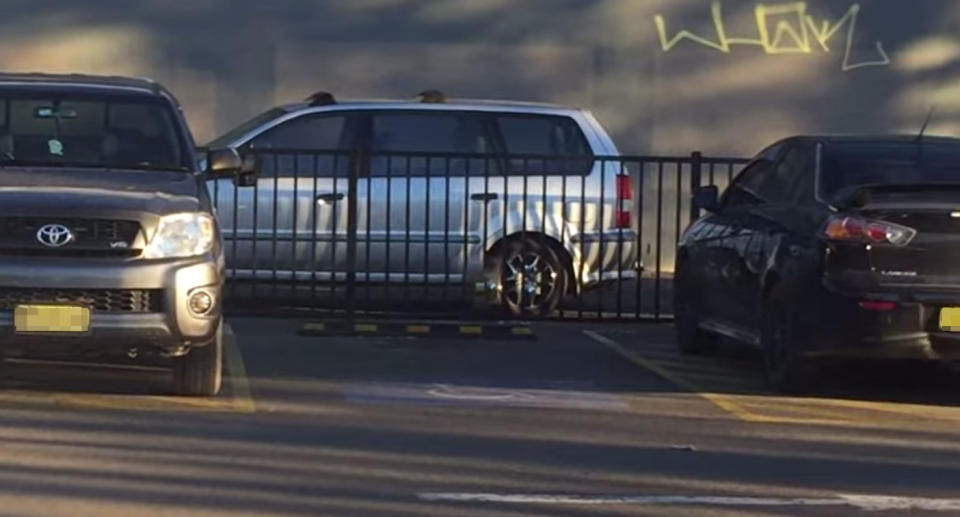 An empty disabled spot seen in a Liverpool parking lot. Two cars are seen blocking the wheelchair access zones marked by yellow lines on either side of the empty space.