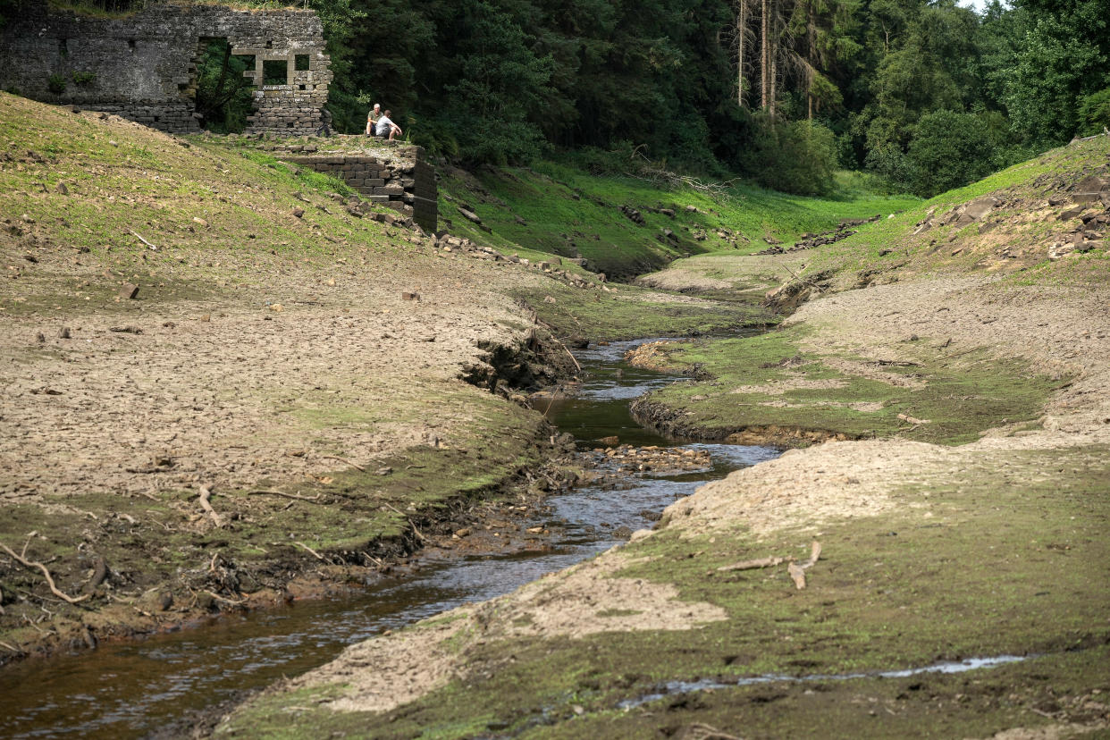 HARROGATE, ENGLAND - JULY 19: People sit on the remnants of the 17th century village of West End which can be seen after water levels in the Thruscross reservoir are partially depleted in the heatwave on July 19, 2022 in Harrogate, England. Yorkshire Water, the regional utility, warned residents to use water wisely during the heatwave, adding that the area has had below average rainfall since last autumn. (Photo by Christopher Furlong/Getty Images)