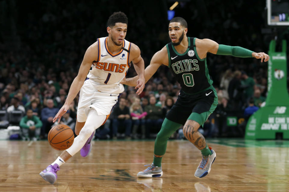 Devin Booker (1) de los Suns de Phoenix se desmarca de Jayson Tatum (0) de los Celtics de Boston, el sábado 18 de enero de 2020. (AP Foto/Mary Schwalm)