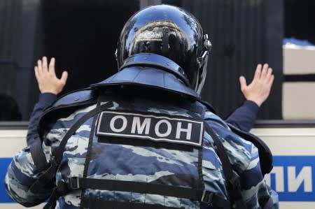 A law enforcement officer detains a man after a rally to demand authorities allow opposition candidates to run in a local election in Moscow