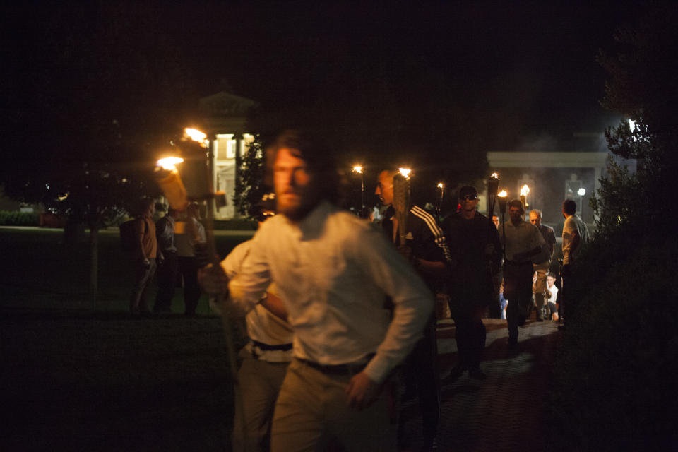 White supremacists, holding torches, take part in a nighttime march.