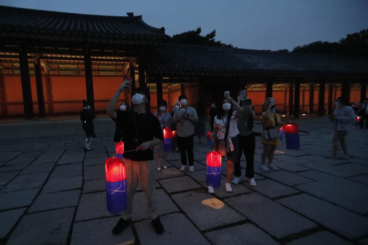 Visitors holding Korean traditional lanterns take pictures during the Moonlight Tour at Changdeokgung Palace in Seoul, South Korea on Thursday, Aug. 13, 2020. The palace reopened Thursday after having been closed for two months due to the coronavirus pandemic.