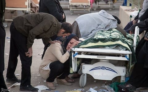 Mourners gather around the body of one of the victims - Credit: Reuters