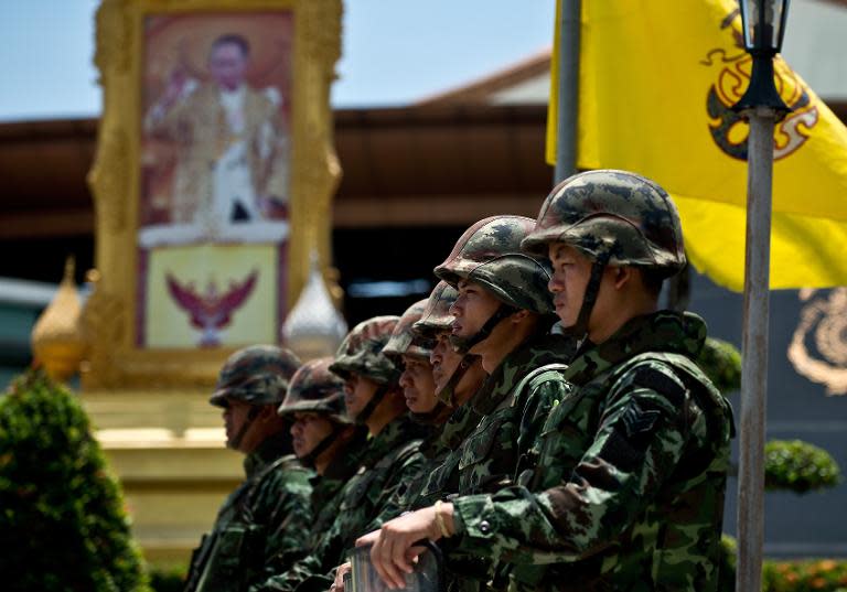 A portrait of Thai King Bhumibol Adulyadej is seen as Thai soldiers stand guard outside the Army club in Bangkok on May 21, 2014