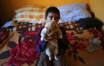 A Roma boy holds his dog in his family's apartment at the Avas apartment block in Miskolc, 180 km (112 miles) east of Budapest October 17, 2012. Spurred by desperate poverty in the nearby countryside, hundreds of destitute Romas moved into local apartment blocks in the last decade. Their presence has caused widespread friction with earlier tenants most of whom are not Roma. Complaining about what they say is a grave deterioration of public safety and insufficient government action to tackle it, the far right Jobbik party announced a big protest march on Wednesday. REUTERS/Laszlo Balogh (HUNGARY - Tags: POLITICS SOCIETY ANIMALS)