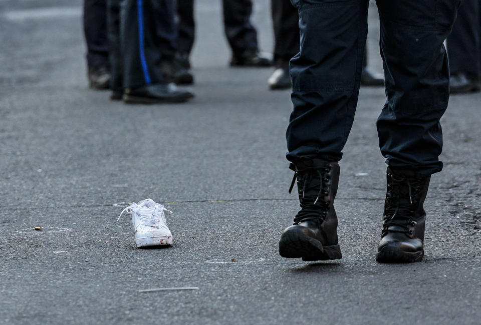 A bloody sneaker lies on the ground as a Philadelphia police officer walks by on the scene in Philadelphia, where a 27-year-old man was fatally shot Monday, Aug. 21, 2023. More than 25 shell casings were found at the scene. (Steven M. Falk/The Philadelphia Inquirer via AP)