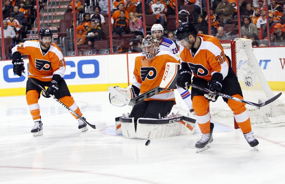 Philadelphia Flyers' Steve Mason, center, makes a save with Andrew MacDonald, left, and Mark Streit, right, of Switzerland, during the second period in Game 6 of an NHL hockey first-round playoff series against the New York Rangers, Tuesday, April 29, 2014, in Philadelphia. (AP Photo/Chris Szagola)