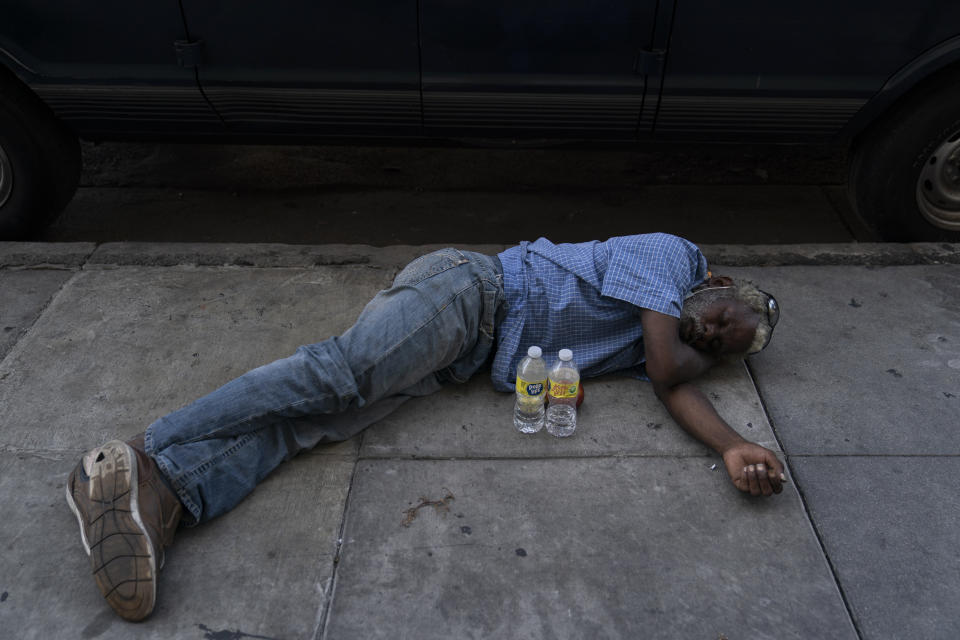 A homeless man naps on a sidewalk with two bottles water in front of him in the Skid Row area of Los Angeles, Wednesday, Aug. 31, 2022. Excessive-heat warnings expanded to all of Southern California and northward into the Central Valley on Wednesday, and were predicted to spread into Northern California later in the week. (AP Photo/Jae C. Hong)
