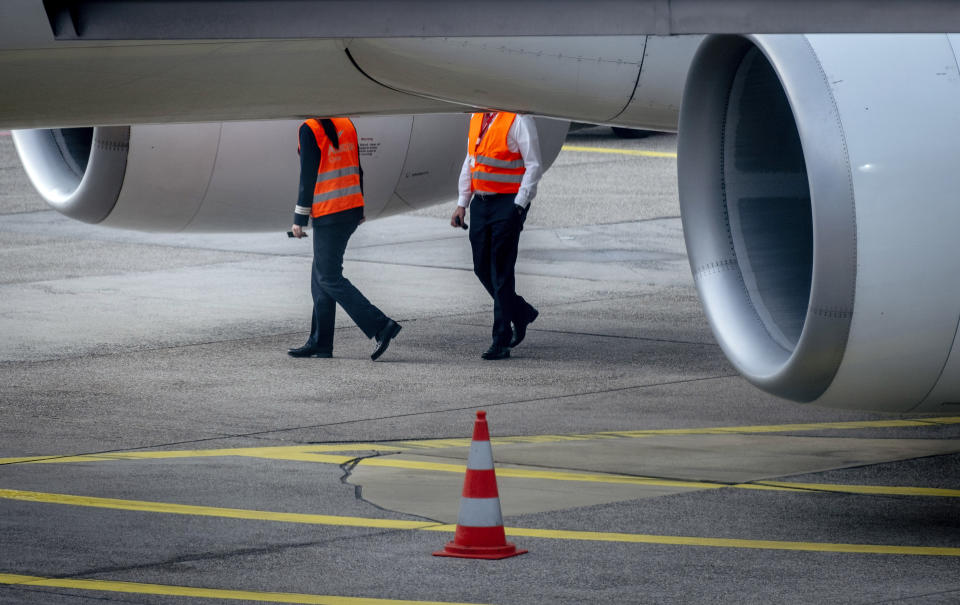 Airport employees walk under an aircraft at the airport in Frankfurt, Germany, Tuesday, Feb. 20, 2024. The trade union Verdi has once again called on Lufthansa ground staff to go on a warning strike. (AP Photo/Michael Probst)