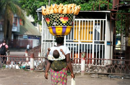 A vendor carries her child on her back as she sells bread along the streets of Democratic Republic of Congo's capital Kinshasa, December 19, 2016. REUTERS/Thomas Mukoya