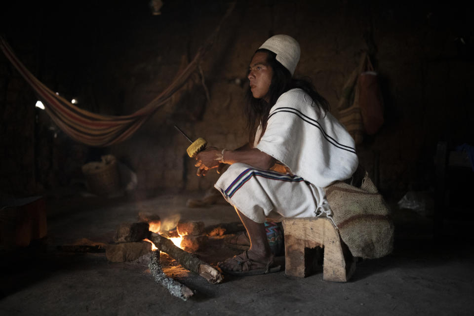 Mariano, a 30-year-old Arhuaco Indigenous man, sits by the fire at his home in Nabusimake on the Sierra Nevada de Santa Marta, Colombia, Tuesday, Jan. 17, 2023. Mariano is a “Mamo” or spiritual leader that keeps his people´s ancient knowledge. (AP Photo/Ivan Valencia)