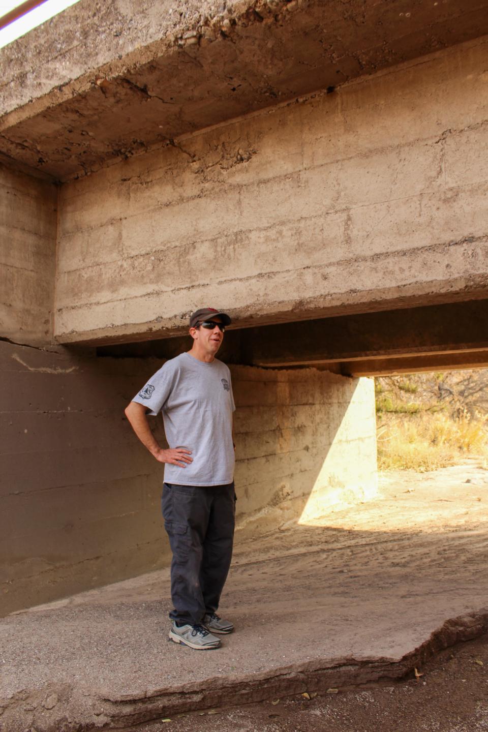 Matthew O'Neill, stands next to a bridge that crosses Boulder Canyon. Before the fire he could walk under the bridge but post fire flooding, triggered by monsoons, pushed several feet of sediment into Boulder Canyon completely covering the rocks below. The Backbone Fire ripped through the area in June 2021 and officially reopened to the public last month.