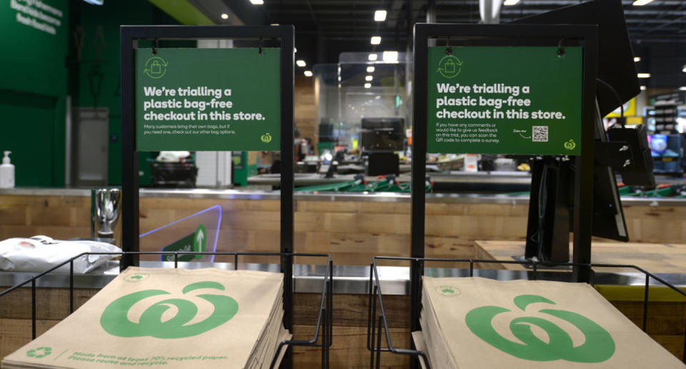 Woolworths paper bags can be seen in store for customers to pick up, with a sign overheard reading, 'We're trialling a plastic bag-free checkout in this store'.