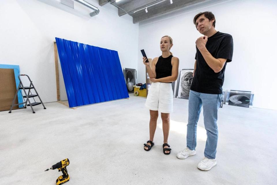 Julia and Max Voloshyn examine a couple of pieces of art that had just been hung on the wall to determined if any adjustments have to be made at the Voloshyn Gallery.