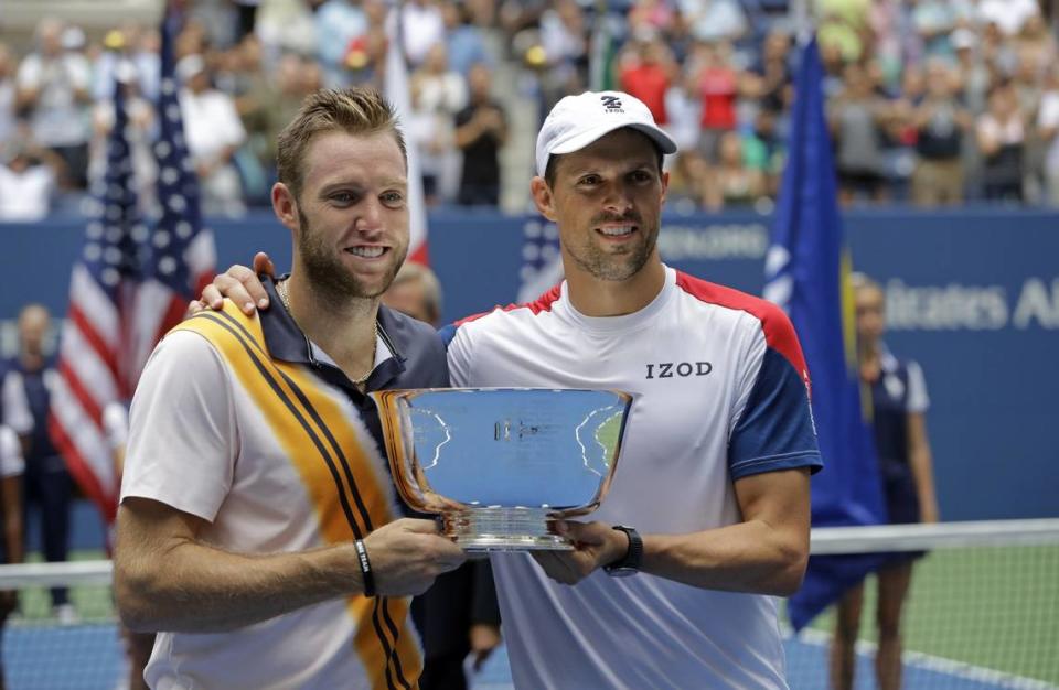 Jack Sock, left, and Mike Bryan hold the trophy after winning the men’s doubles final at the 2018 U.S. Open. Sock led all pro players that year in doubles titles, but his singles game started to slide.