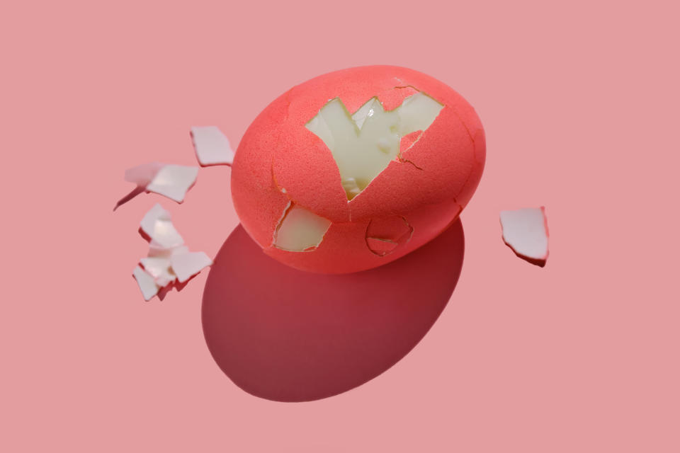 Cracked hardboiled egg that's dyed red on plain background