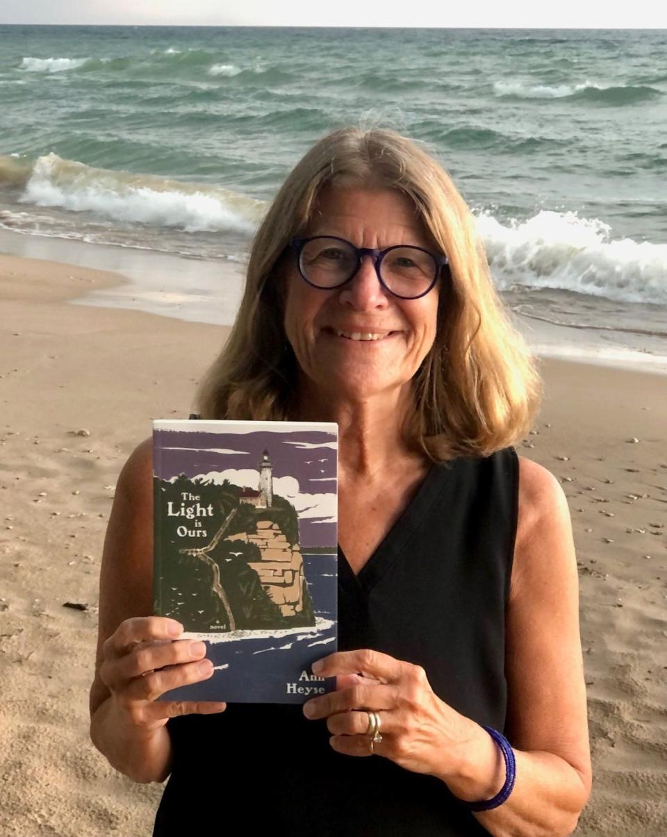 Writer Ann Heyse holds a copy of her new historical fiction book, "The Light is Ours," on the Lake Michigan shore in Door County. It's Heyse's first full-length novel, set at a fictional Door County lighthouse in the 1870s, after she wrote two children's books and a poetry collection.
