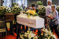 Mourners stand by a small white coffin prior to the funeral service of some of the victims of a collapsed highway bridge, in Genoa, Italy, Saturday, Aug. 18, 2018. Saturday has been declared a national day of mourning in Italy and includes a state funeral at the industrial port city's fair grounds for those who plunged to their deaths as the 45-meter (150-foot) tall Morandi Bridge gave way Tuesday. (AP Photo/Nicola Marfisi)