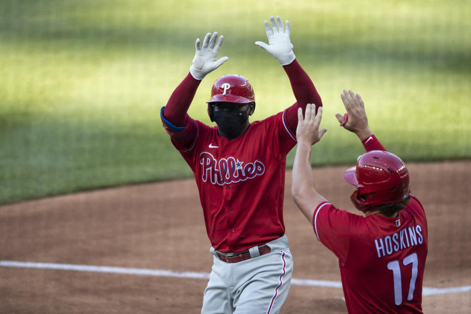 Philadelphia Phillies' Didi Gregorius celebrates without touching, while wearing a mask, his three-run homer with Rhys Hoskins during the first inning of an exhibition baseball game against the Washington Nationals at Nationals Park, Saturday, July 18, 2020, in Washington. (AP Photo/Alex Brandon)