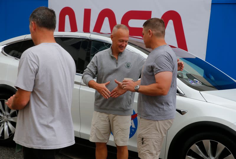 NASA astronauts Douglas Hurley and Robert Behnken shake hands after placing decals on their crew car at the Kennedy Space Center