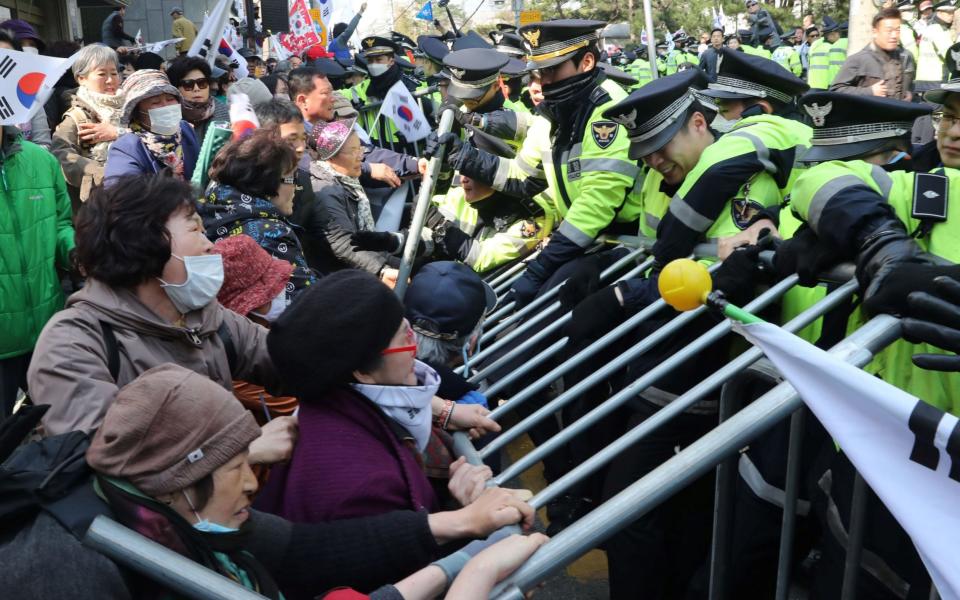 Supporters of South Korea's ousted president Park Geun-Hye clash with police outside Park's home as she leaves for the hearing - Credit: AFP