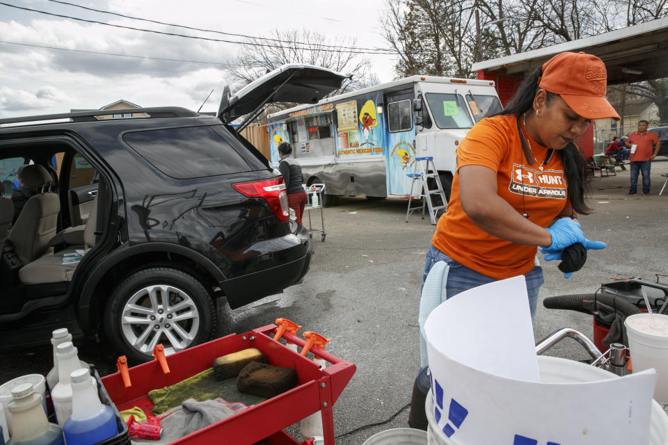 Esperanza Carrillo, of Burlington, N.C., washes cars at Vivas Hand Car Wash, Wednesday, March 11, 2020, along a strip of Latino owned businesses. (AP Photo/Jacquelyn Martin)