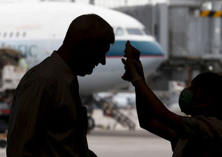 A flight passenger receives a temperature check upon his arrival at Hong Kong Airport in Hong Kong, China June 5, 2015. REUTERS/Bobby Yip - RTX1F7MM