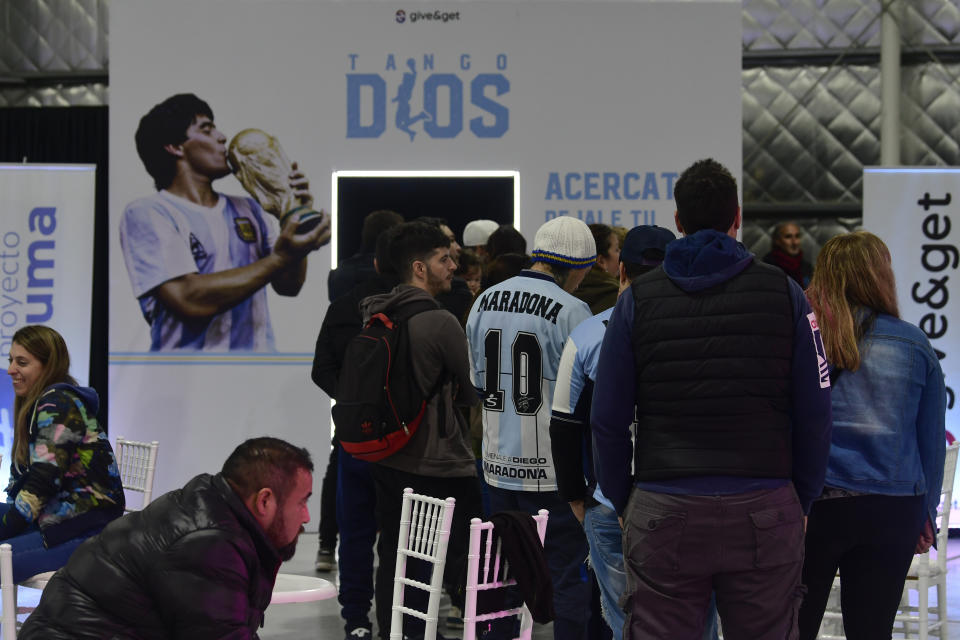 Aficionados aguardan para grabar un mensaje al astro del fútbol Diego Maradona durante la presentación de una aeronave dedicada al fallecido futbolista, en una base militar en Morón, en las afueras de Buenos Aires, Argentina, el sábado 23 de julio de 2022. El avión partirá después en una gira por el mundo, que visitará Brasil, Colombia, México y Estados Unidos antes de llegar a Europa y hacer parada en Roma y Nápoles _dos lugares míticos en la carrera del 10_ y aterrizar en el Mundial de Catar. (AP Foto/Gustavo Garello)