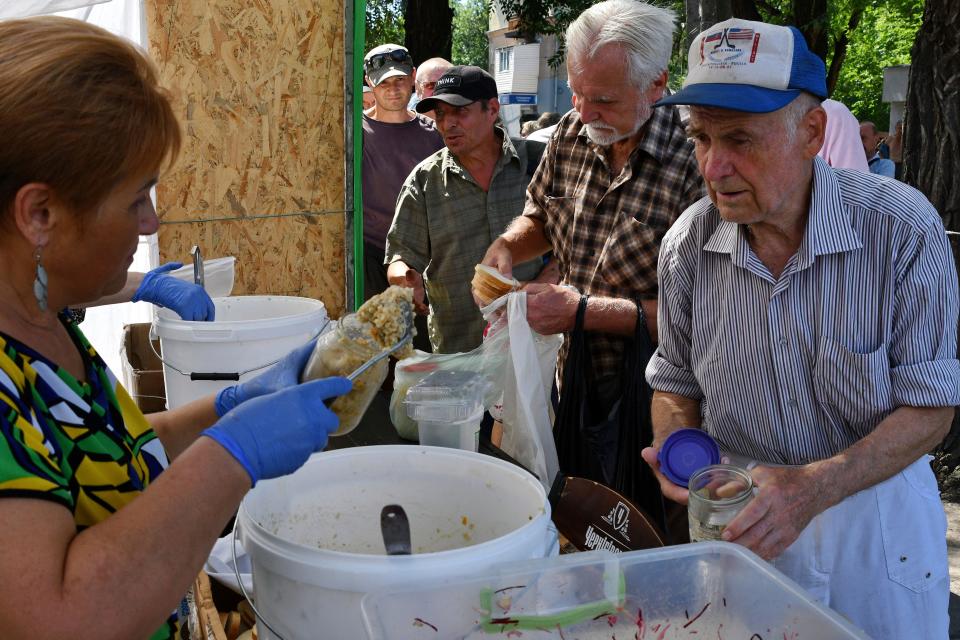 People receive food at a humanitarian aid distribution point in Zaporizhzhia, Ukraine, Tuesday, Aug. 9, 2022.