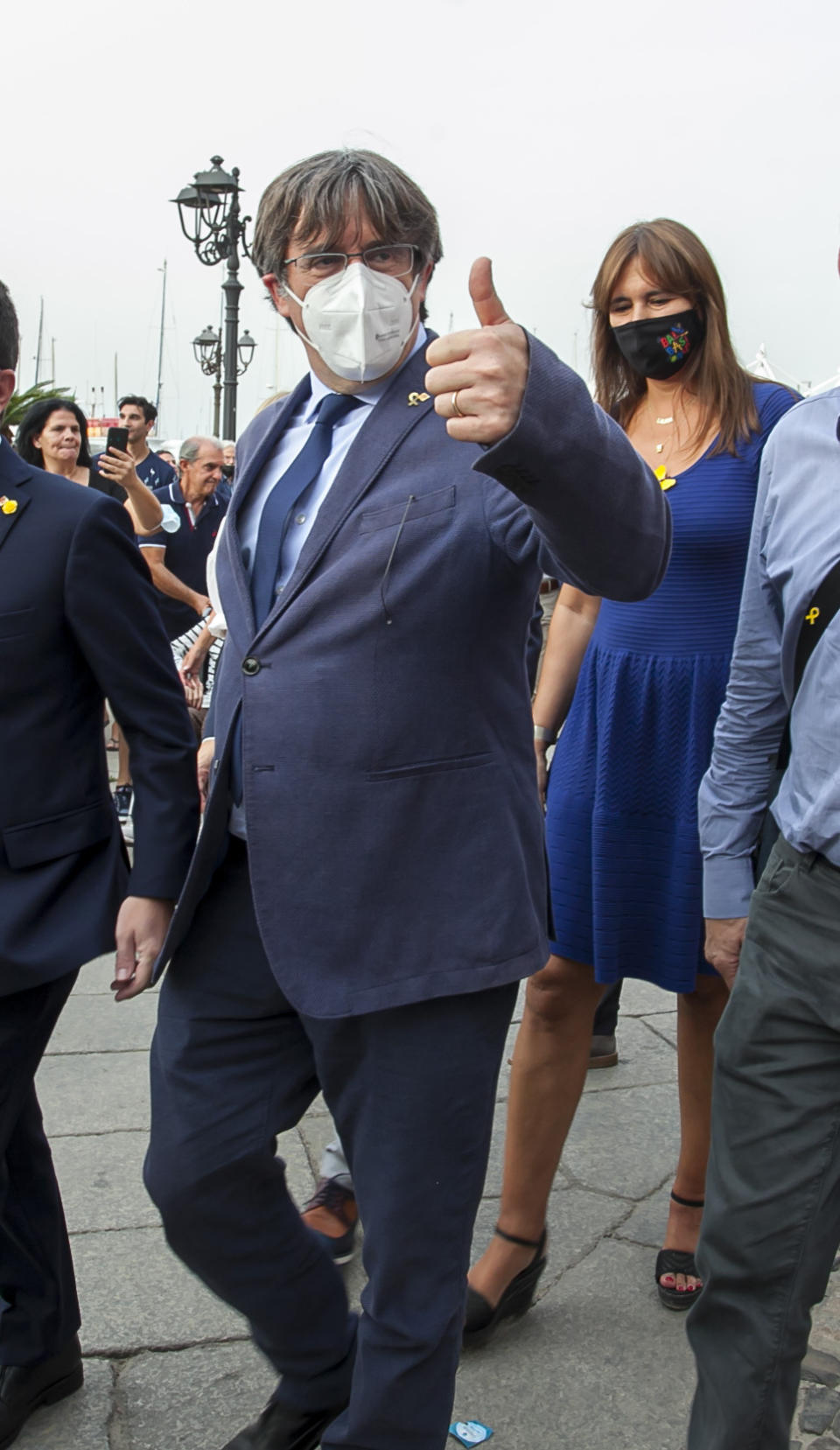 Catalan separatist leader Carles Puigdemont, left, gives thumbs up as he walks with the Speaker of the Catalan Parliament Laura Borras in Alghero, Sardinia, Italy, Saturday, Sept. 25, 2021. Puigdemont took a leisurely walk in the Sardinian city, waving to supporters, a day after a judge freed him from jail pending a hearing on his extradition to Spain, where the political firebrand is wanted for sedition. (AP Photo/Francesca Salaris)