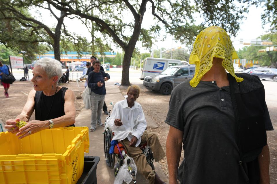 Diane Holloway, the community engagement coordinator at Sunrise Homeless Navigation Center, gives ice-cold bandannas to Joe Mullins and other people experiencing homelessness on Tuesday during a heat advisory.