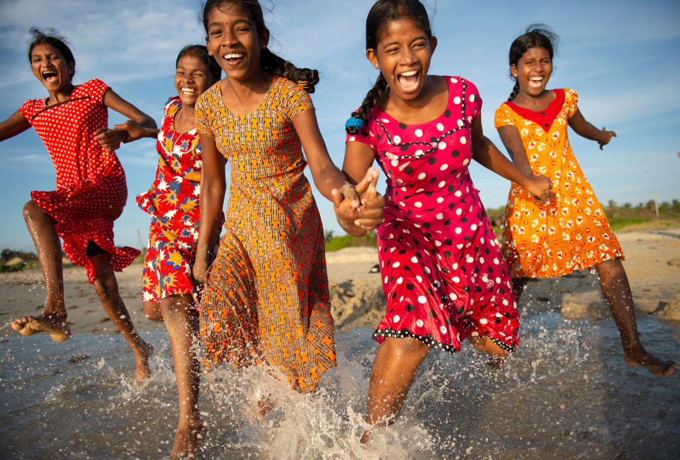 women in bright dresses holding hands